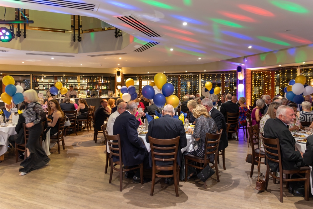 Guests seated at round banquet tables with balloon centerpieces during an evening gala dinner and party at CIM Business Centre.