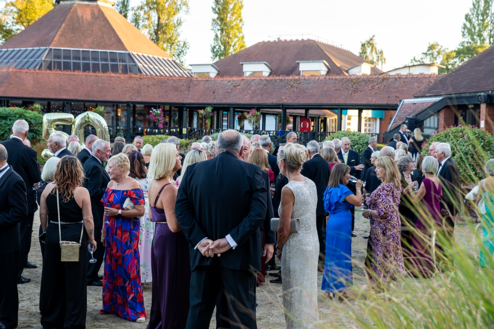 Guests in evening formal wear enjoying an outdoor drinks reception in the courtyard at CIM Business Centre during a celebration event.