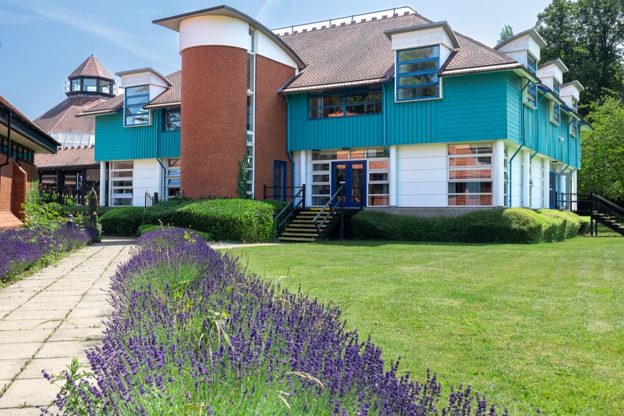 Exterior view of the modern CIM Business Centre facility featuring landscaped lawns and a lavender-lined stone pathway.