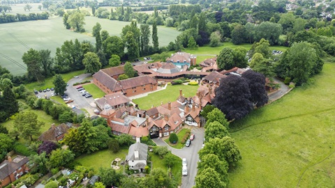 High-angle aerial drone view showing the full CIM Business Centre complex, surrounded by landscaped grounds and open green countryside.